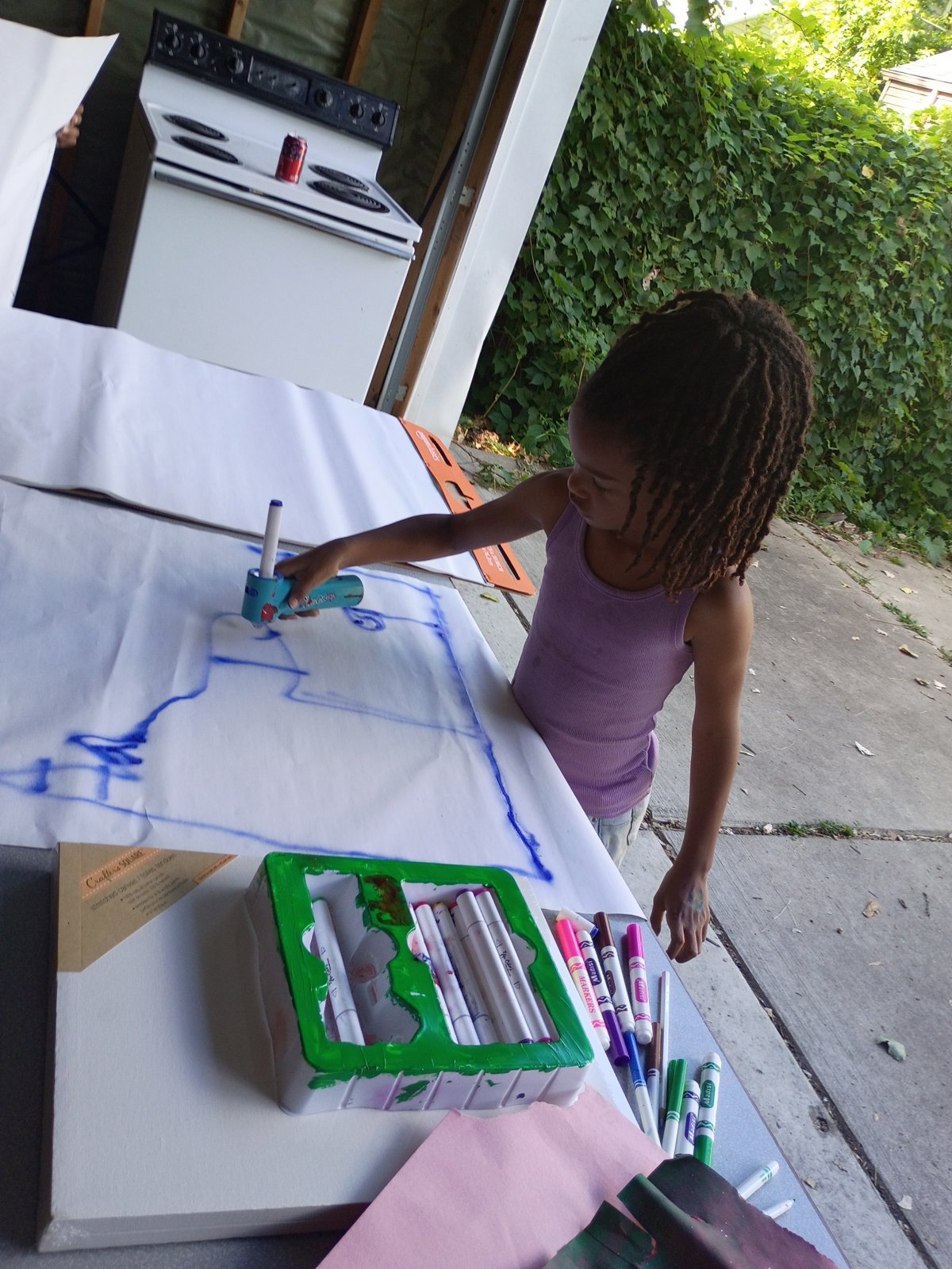 A young artist painting at a table in the garage art space